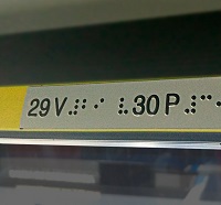 Placas com a numeração dos assentos e informação sobre segurança em braille.